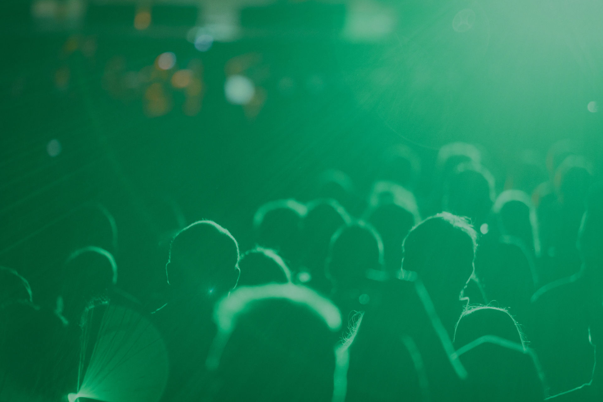 Público con los brazos en alto en un concierto con iluminación verde en Gran Canaria